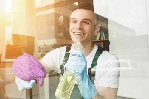 worker using cleaning solution to clean the inside of window