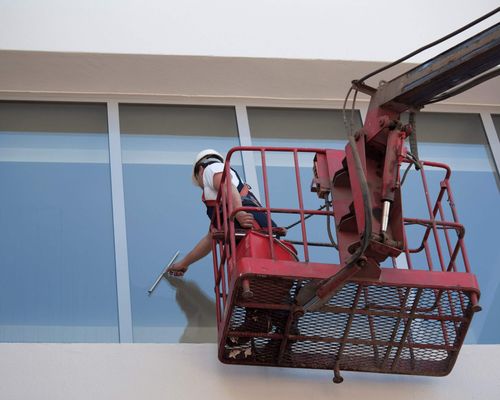 worker cleaning window of office building
